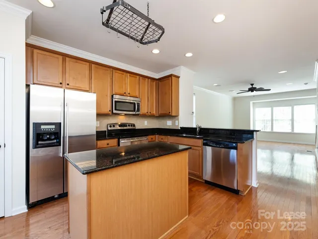 a kitchen with stainless steel appliances granite countertop a refrigerator a stove a sink and a microwave
