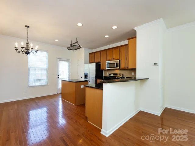 a kitchen with stainless steel appliances granite countertop a refrigerator a stove top oven a sink dishwasher and wooden floor