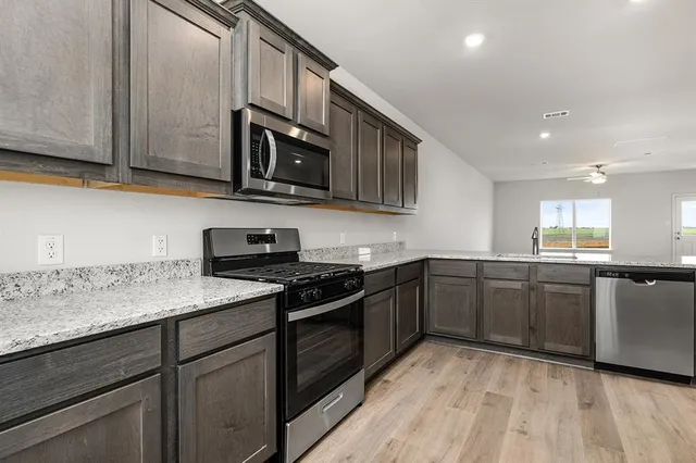 a kitchen with stainless steel appliances granite countertop wooden cabinets a stove top oven a sink and dishwasher