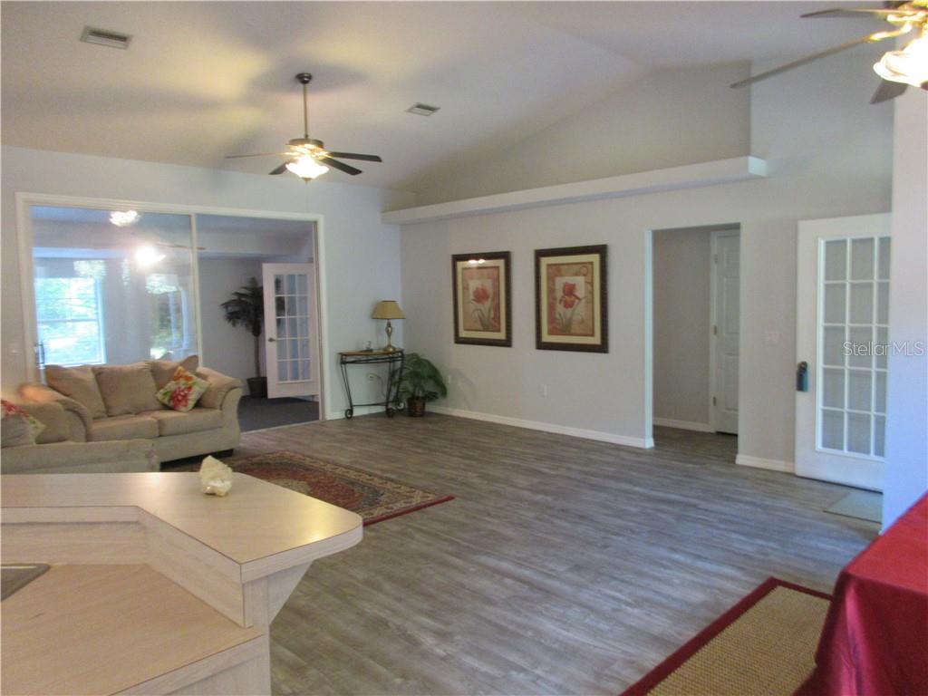 VIEW OF GREAT ROOM FROM KITCHEN TO SHOW FRONT DOOR ON RIGHT. HALL TO 3 BEDS AND HALL BATH. PLANT SHELVES.