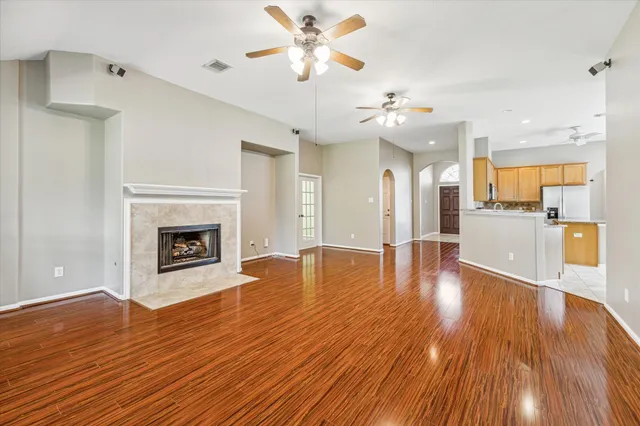 a view of a kitchen with a fireplace a ceiling fan and wooden floor