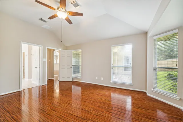 a view of an empty room with wooden floor and a window