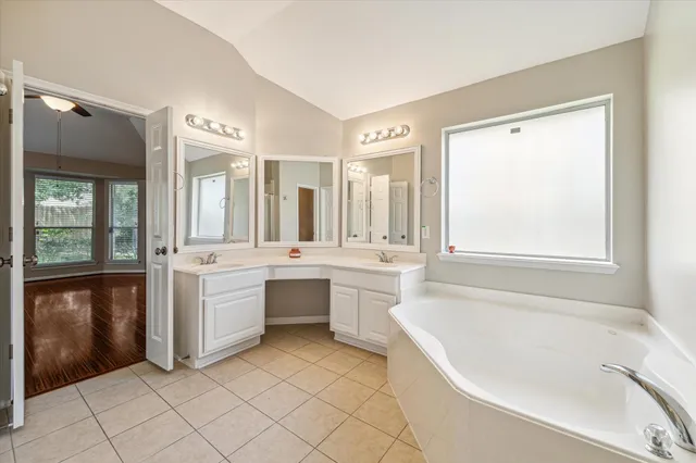 a large white bathroom with a large tub sink shower and mirror