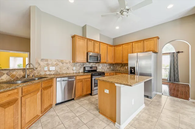a kitchen with stainless steel appliances granite countertop a sink stove refrigerator and cabinets
