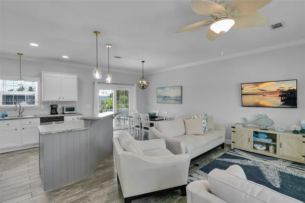a living room with furniture kitchen view and a wooden floor