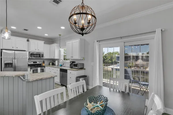 a kitchen with stainless steel appliances granite countertop a stove a refrigerator a oven a sink a dining table and chairs with wooden floor