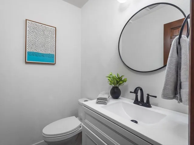 a bathroom with a granite countertop sink toilet and mirror