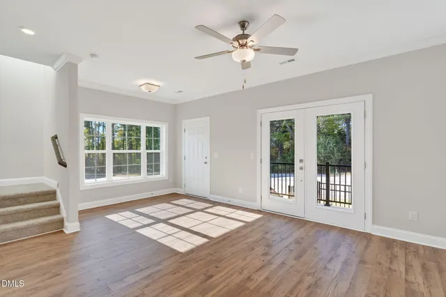 a view of an empty room with a window and wooden floor
