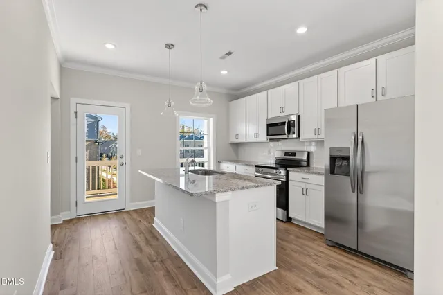 a kitchen with stainless steel appliances granite countertop a refrigerator a stove top oven a sink dishwasher and a refrigerator with wooden floor