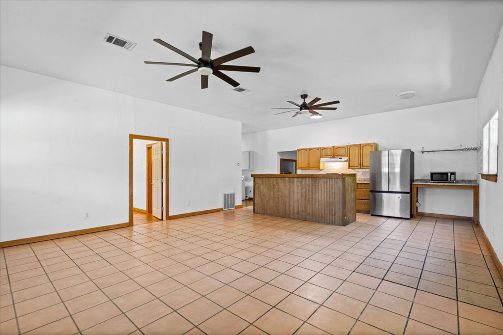 555 Harmon Hills Road, Unit A Dripping Springs, TX 78620 - Photo 3 of 29 A spacious, naturally illuminated room boasts an open-concept kitchen and durable tile flooring throughout.