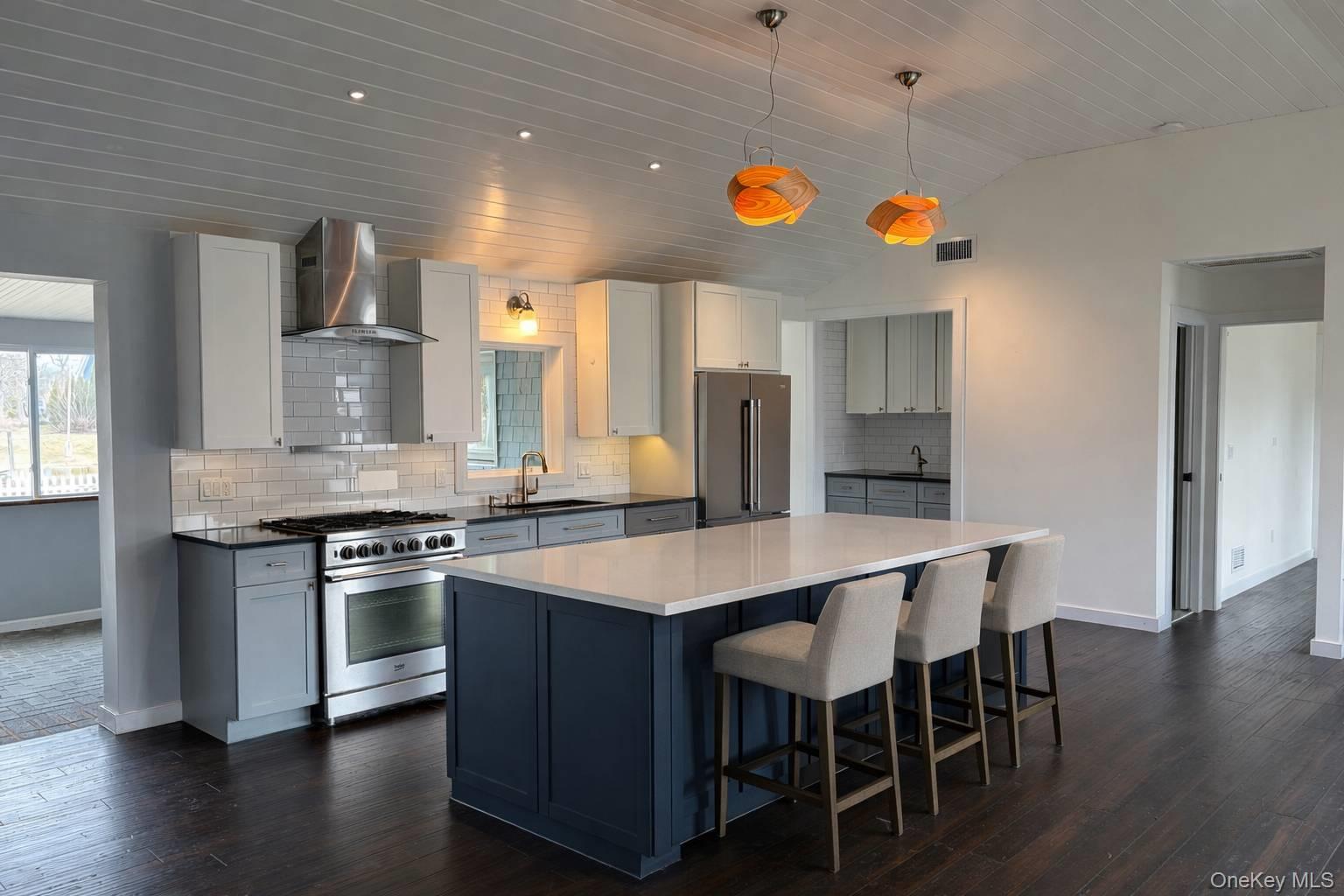 21 Tarpon Road East Quogue, NY 11942 - Photo 8 of 18 a kitchen with stainless steel appliances a dining table and chairs