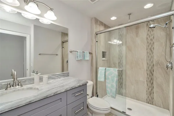 a bathroom with a granite countertop sink toilet a shower and a mirror