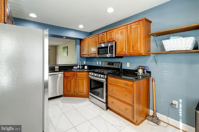 a kitchen with stainless steel appliances granite countertop a stove a sink and a refrigerator