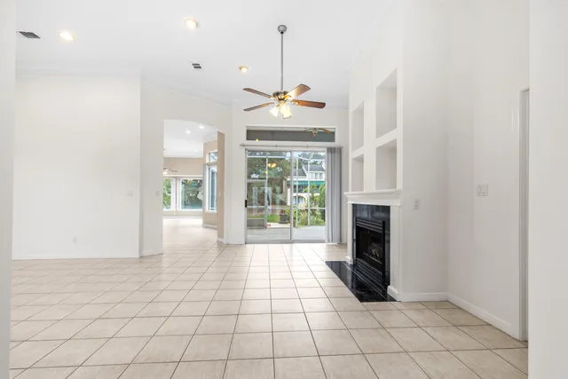 an empty room with wooden floor fireplace and windows