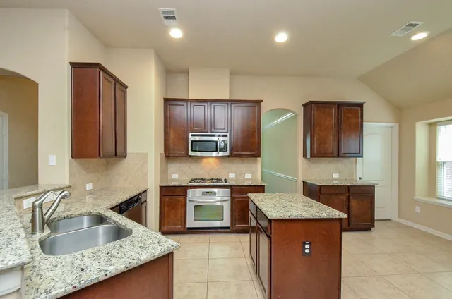 a kitchen with stainless steel appliances granite countertop a sink counter space cabinets and a large window