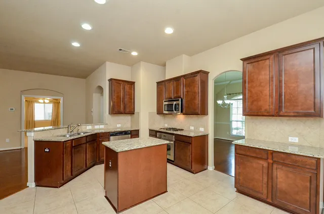 a kitchen with kitchen island granite countertop wooden cabinets a sink and a stove
