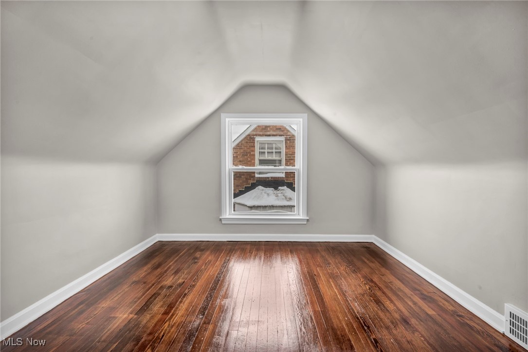 13614 Cedar Road Cleveland, OH 44118 - Photo 31 of 46 Additional living space featuring baseboards, vaulted ceiling, visible vents, and dark wood finished floors