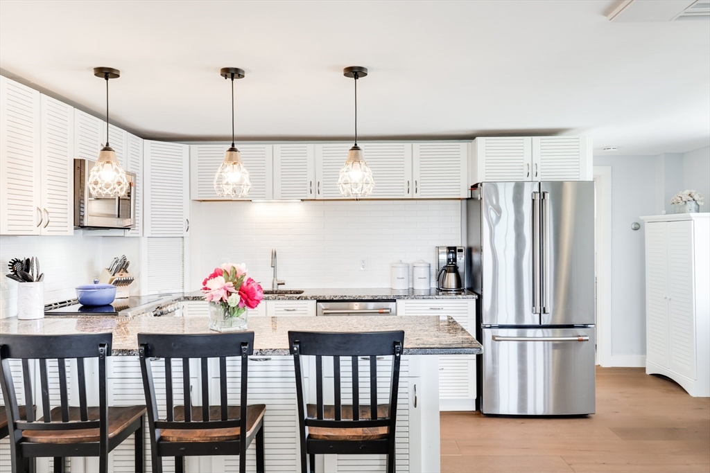 213 Phillips Road Sandwich, MA 02563 - Photo 17 of 36 a kitchen with stainless steel appliances granite countertop a refrigerator a sink dishwasher a dining table and chairs with wooden floor