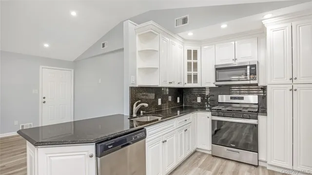 a kitchen with granite countertop a sink stove and cabinets