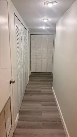 a view of a hallway with wooden floor and entryway