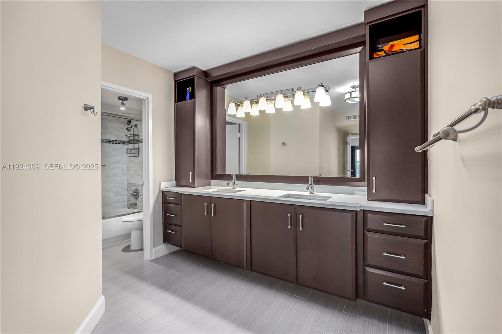 9225 Collins Avenue, Unit 612 Surfside, FL 33154 - Photo 13 of 38 a bathroom with a double vanity sink and a mirror