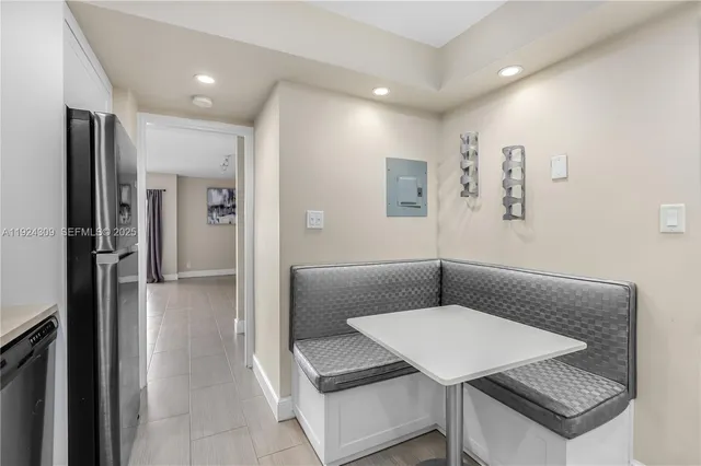 a living room with stainless steel appliances furniture a refrigerator and a kitchen view