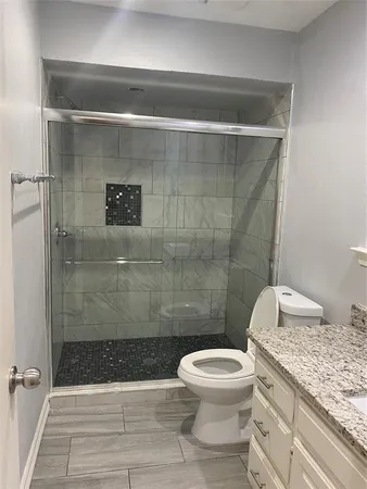 a bathroom with a granite countertop toilet a sink and shower