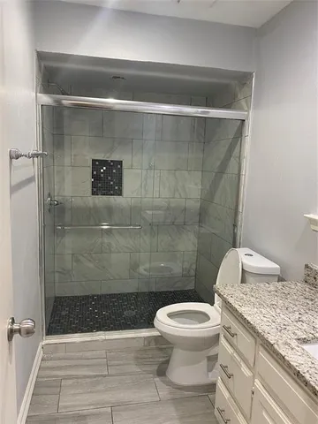 a bathroom with a granite countertop toilet a sink and shower
