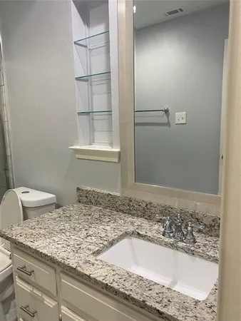 a bathroom with a granite countertop sink and a toilet