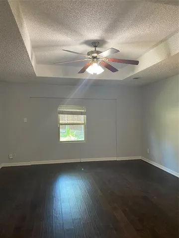 an empty room with wooden floor chandelier fan and windows