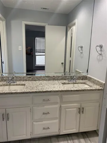 a bathroom with a granite countertop sink and white cabinets