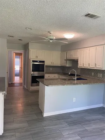 a large kitchen with stainless steel appliances granite countertop a stove a sink and a granite counter tops with white cabinets