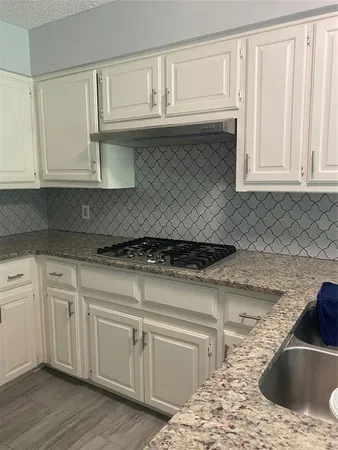 a kitchen with granite countertop a sink cabinets and a wooden floor