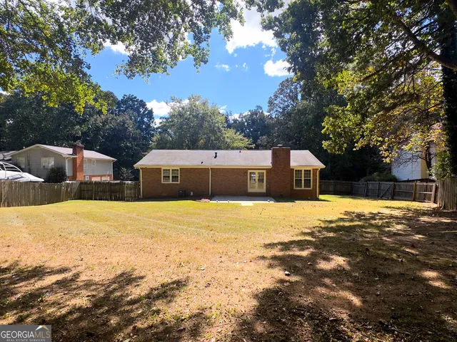 a tall yellow house with a large tree in front of it