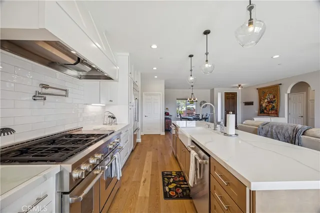 a large kitchen with kitchen island a stove a sink a refrigerator and a dining table view