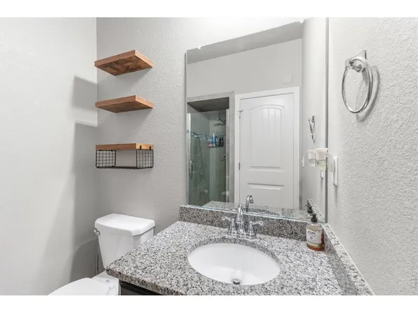 a bathroom with a granite countertop sink toilet and a mirror