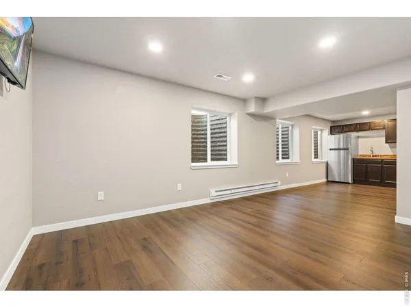 a view of an empty room with a window and wooden floor