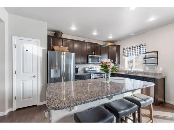 a kitchen with kitchen island granite countertop a refrigerator and a stove top oven