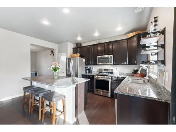 a kitchen with kitchen island granite countertop stainless steel appliances cabinets a sink and a center island
