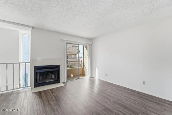 a view of an empty room with wooden floor fireplace and a window