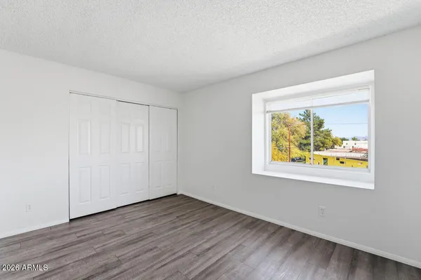 a view of an empty room with wooden floor and a window