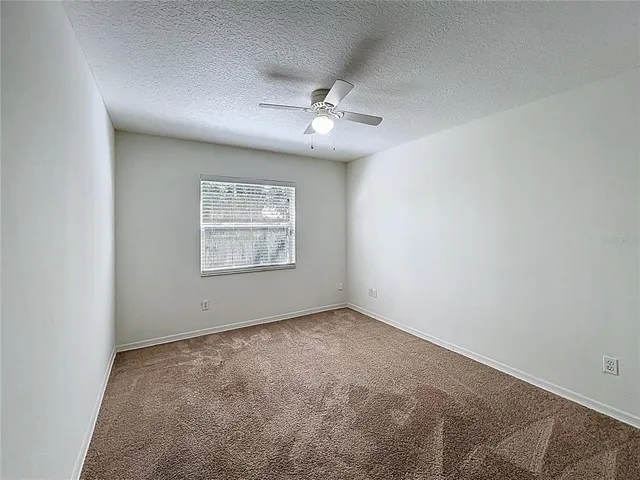 a view of an empty room with a chandelier fan