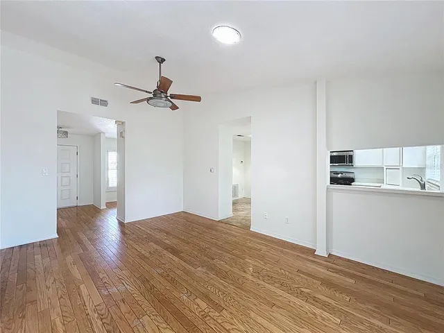 a view of empty room with wooden floor and ceiling fan