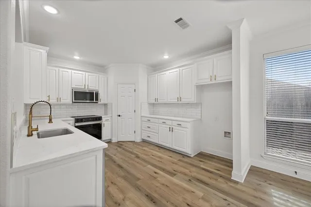 a kitchen with a refrigerator stove and white cabinets