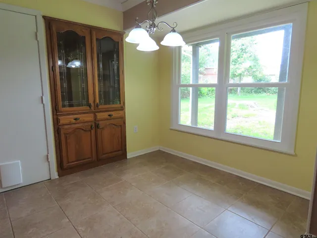 a view of an empty room with window chandelier fan