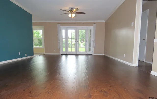 a view of an empty room with wooden floor and a window