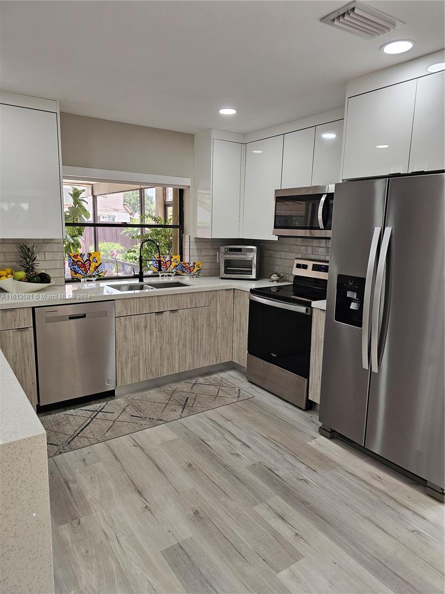 4323 Southwest 148th Place Miami, FL 33185 - Photo 17 of 70 a kitchen with stainless steel appliances granite countertop a stove top oven a refrigerator and a sink