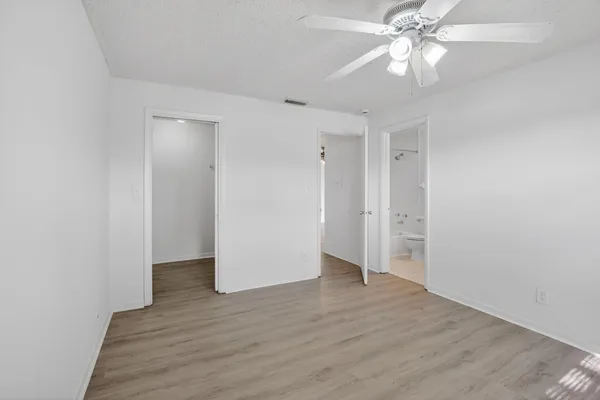 an empty room with wooden floor and ceiling fan