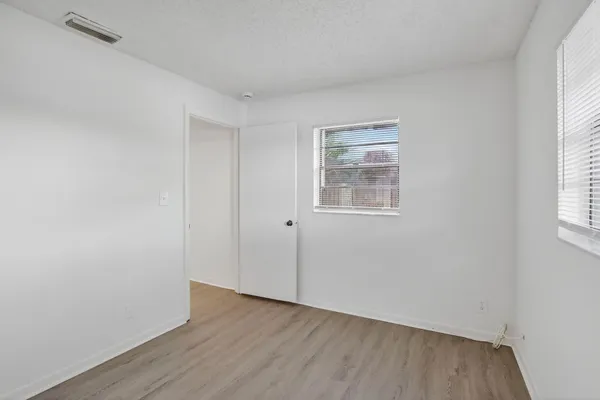 an empty room with wooden floor and windows