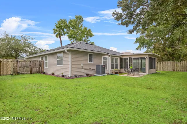 a backyard of a house with table and chairs plants and large tree